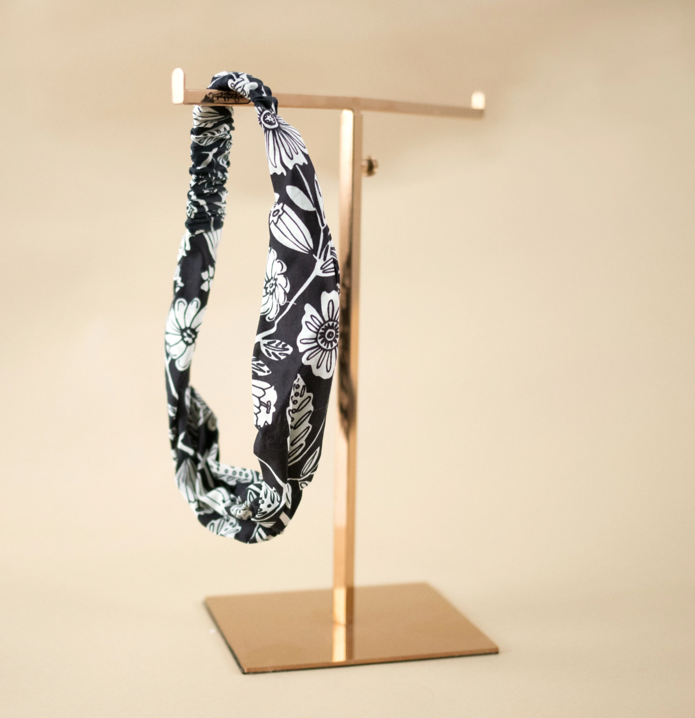 the fiona headband features a navy + white floral print. hanging on a display stand